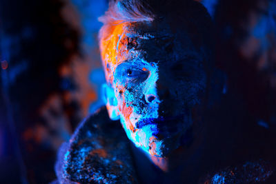 Close-up portrait of man covered with powder paint against black background