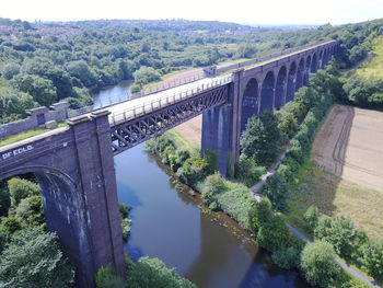 Bridge over river amidst trees against sky