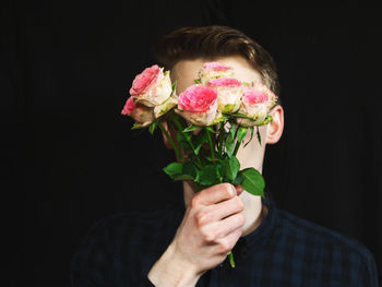 Man holding bouquet against black background