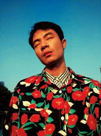 Portrait of young man standing against blue sky