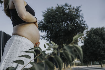 Mid section of pregnant woman standing outdoors