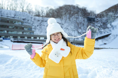 Portrait of smiling young woman standing on snow