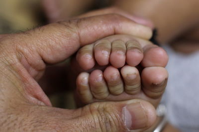 Close-up of grandfather hands holding baby foot