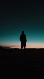 Rear view of silhouette man standing against clear sky during sunset