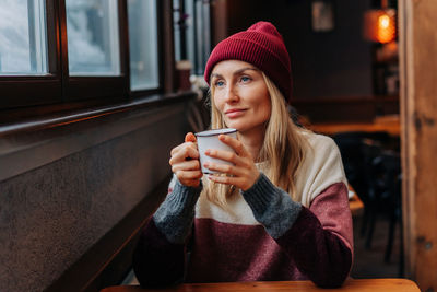 Apres ski, a woman in a coffee sitting in a cozy bar drinks coffee.