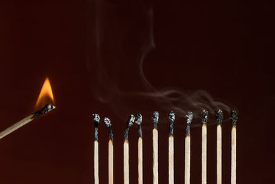 Close-up of burning candles against black background