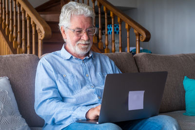 Man using laptop while sitting on sofa at home