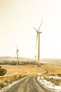 Wind turbines in field against clear sky