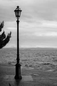 Street light by sea against sky