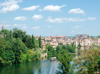 Scenic view of river by buildings against sky