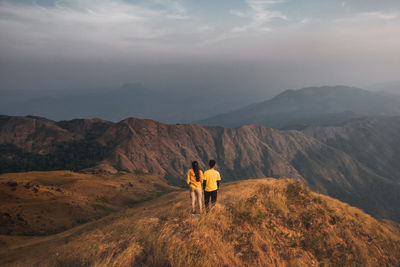 Rear view of men standing on mountain against sky