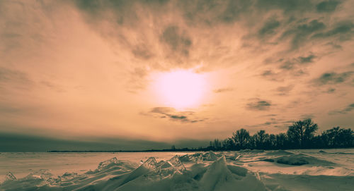 Scenic view of snow covered land against sky during sunset