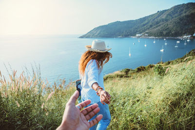 Woman with arms raised on shore against sky