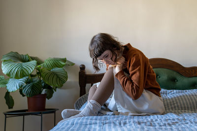 Feeling desperate frustrated confused depressed teenage girl sitting in closed pose in bed at home.