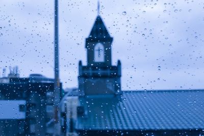 Buildings seen through wet glass window during rainy season