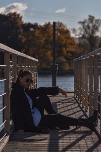 Rear view of woman sitting on railing