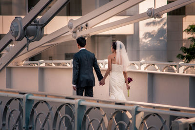 Rear view of man and woman walking on railing