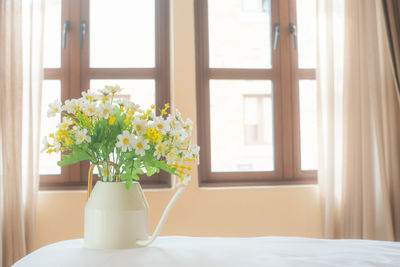 Flower vase on table by window at home