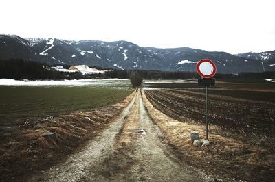 Road sign on snow covered mountain against clear sky