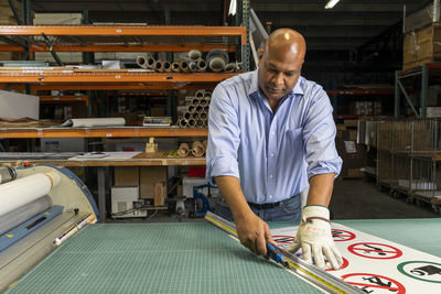 Male supervisor cutting paper signs on workbench