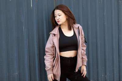 Young woman standing against wall