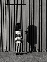 Rear view of girl standing by corrugated door