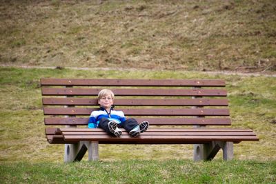 Boy sitting on bench in park