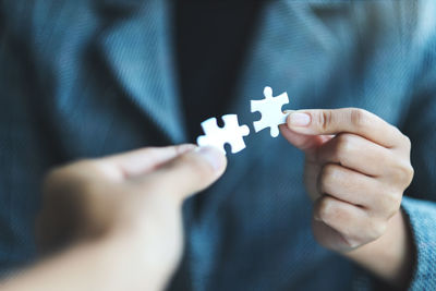 Midsection of man holding jigsaw pieces