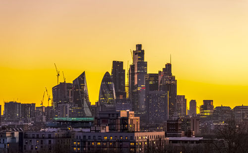 Buildings in the city against sky during sunset