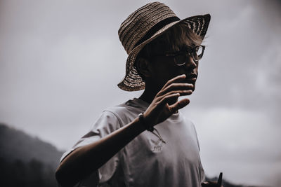 Portrait of person wearing hat standing against sky