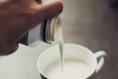 Close-up of hand pouring milk in cup