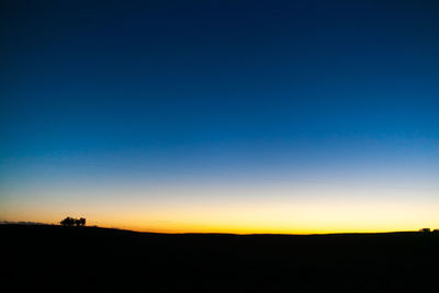 Silhouette landscape against clear sky during sunset
