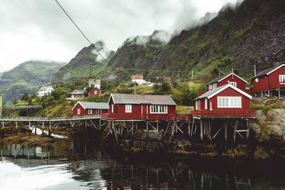 Houses by lake and mountains against sky