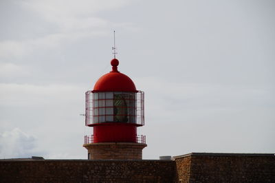 Lighthouse by wall against sky