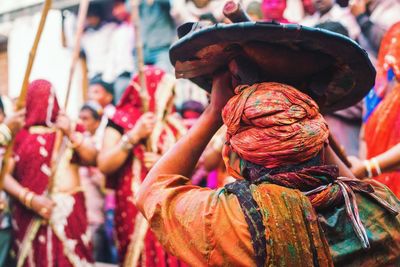 Rear view of man in traditional clothing carrying container on head