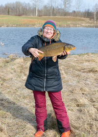  a happy fisherman on the lake shore, caught carp in a woman's hand, amateur carp fishing