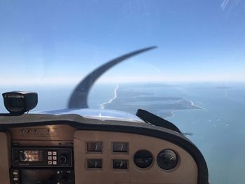 Close-up of airplane flying over sea against blue sky