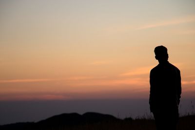 Silhouette man standing against orange sky