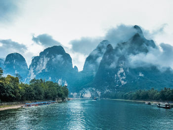 Scenic view of river and mountains against sky