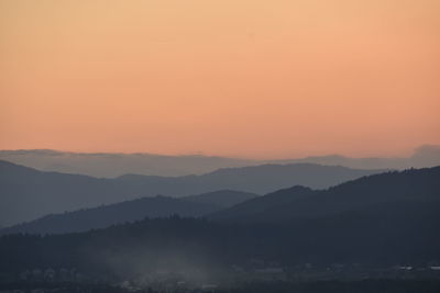 Scenic view of silhouette mountains against orange sky