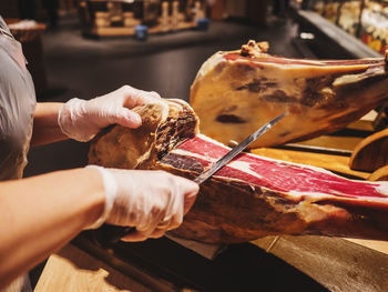 Midsection of butcher cutting meat at store