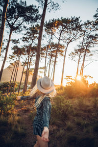 Woman standing against trees during sunset