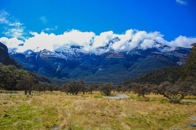 Scenic view of landscape and mountains against blue sky