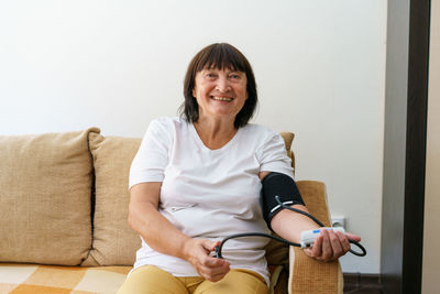 Adult female person measuring her blood pressure and pulse with an electronic