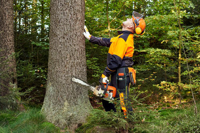 Full length of father and son on tree trunk in forest