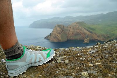 Low section of man standing on rock by sea