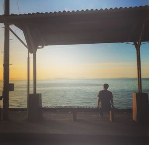 Rear view of man looking at sea against sky