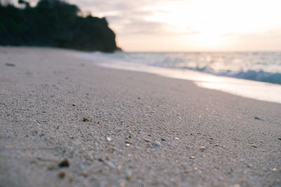 Surface level of beach against sky during sunset