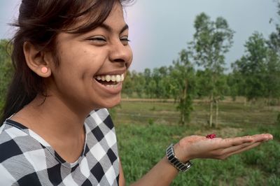 Girl laughing on field against trees