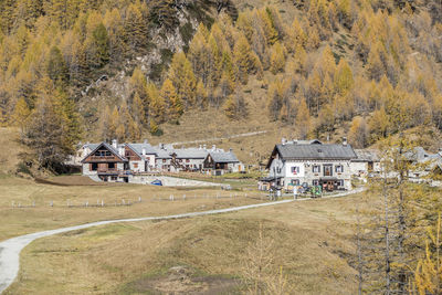 Houses on field by trees and mountains during autumn